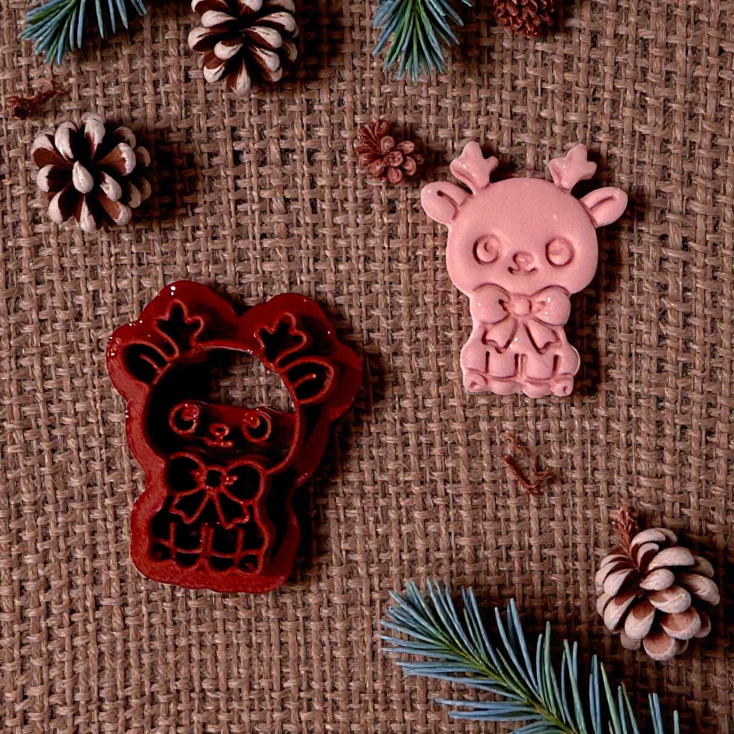 red reindeer cutter beside pink clay impression on burlap