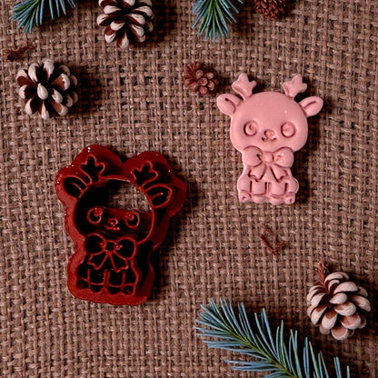 red reindeer cutter beside pink clay impression on burlap