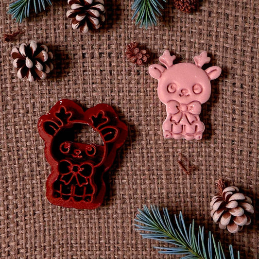 red reindeer cutter beside pink clay impression on burlap