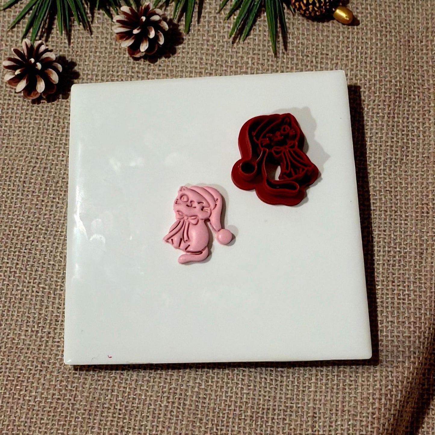 Cutter and clay kitty displayed with pinecones and greenery