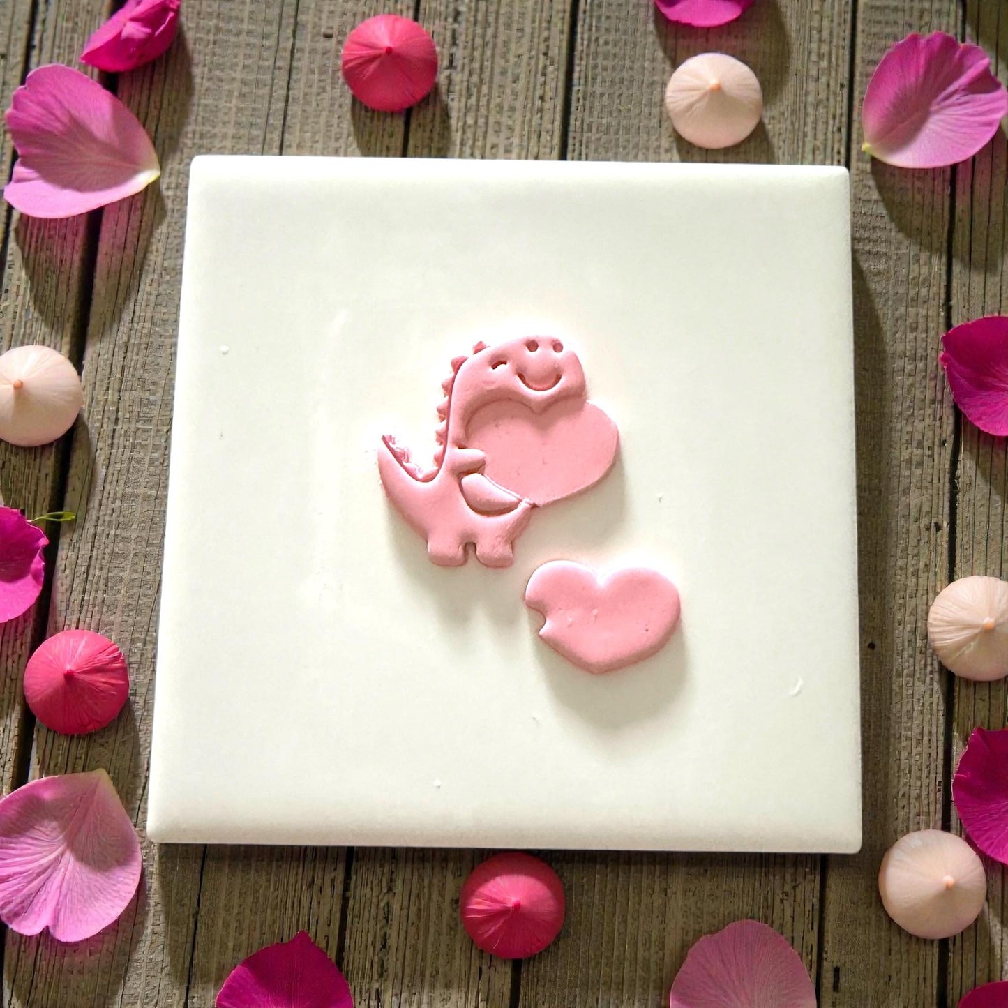 Dino heart polymer clay cutter pressed into pink clay with sprinkles around