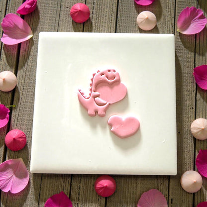 Dino heart polymer clay cutter pressed into pink clay with sprinkles around