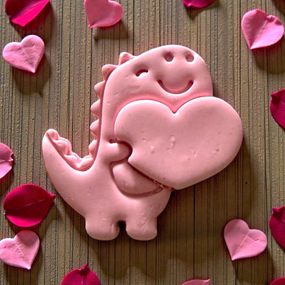 Close-up of pink clay dino holding a heart with flower petals
