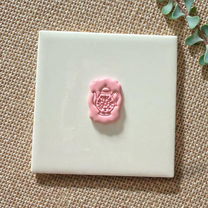 floral teapot cutter and pink clay impression side by side