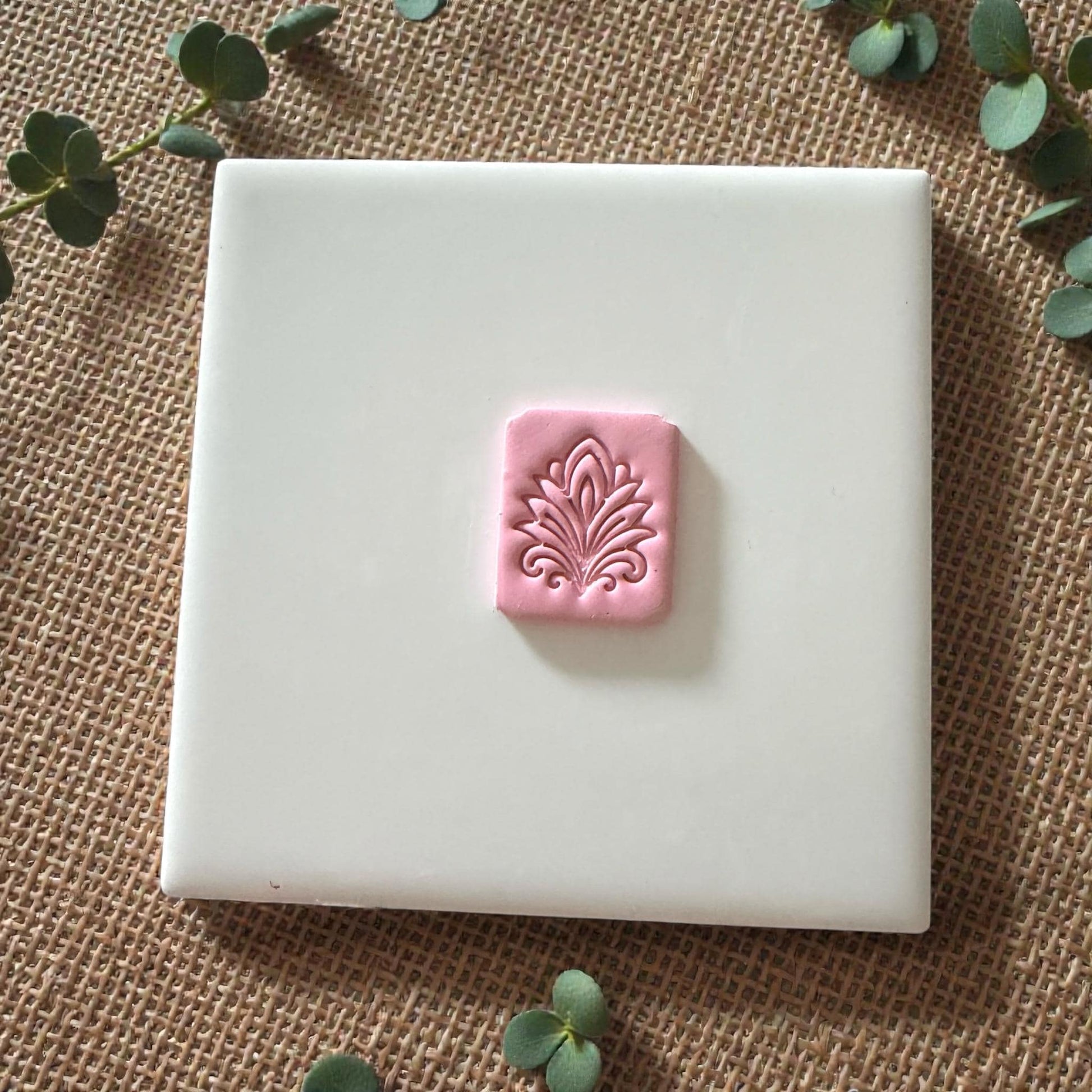 small pink clay tile with floral pattern on white background