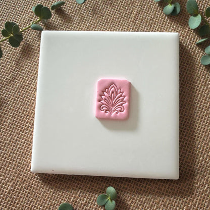 small pink clay tile with floral pattern on white background