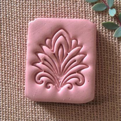 close-up pink clay impression of ornate leaf design