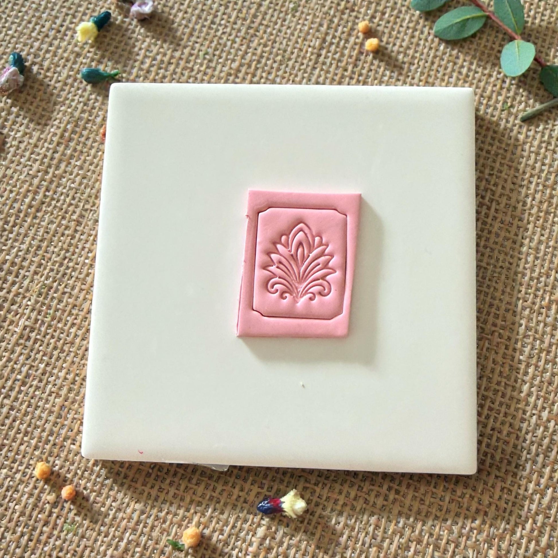 pink clay tile with ornate embossed border and floral design