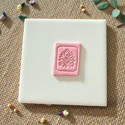 pink clay tile with ornate embossed border and floral design
