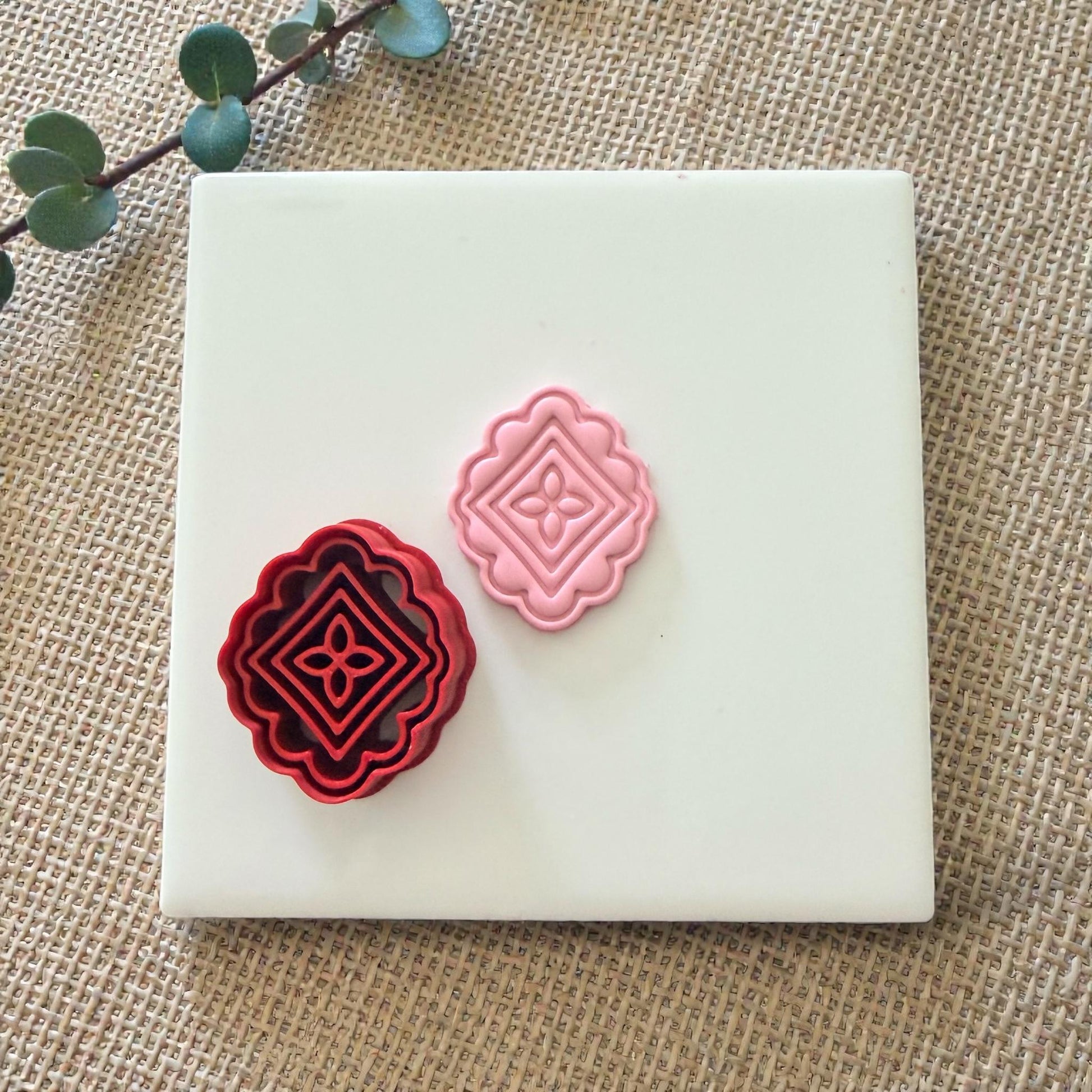 scalloped tile cutter and pink clay stamp on white tile