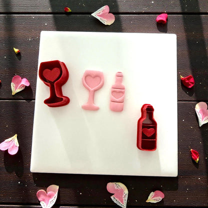 Wine glass and bottle clay cutters with pink clay impressions on white tile