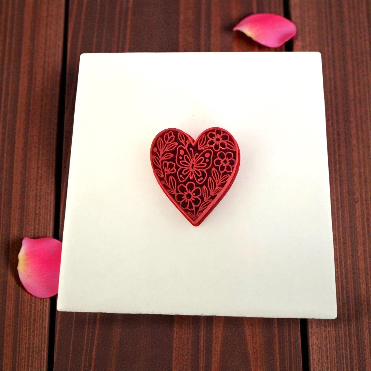 red floral heart cutter on white tile with petals