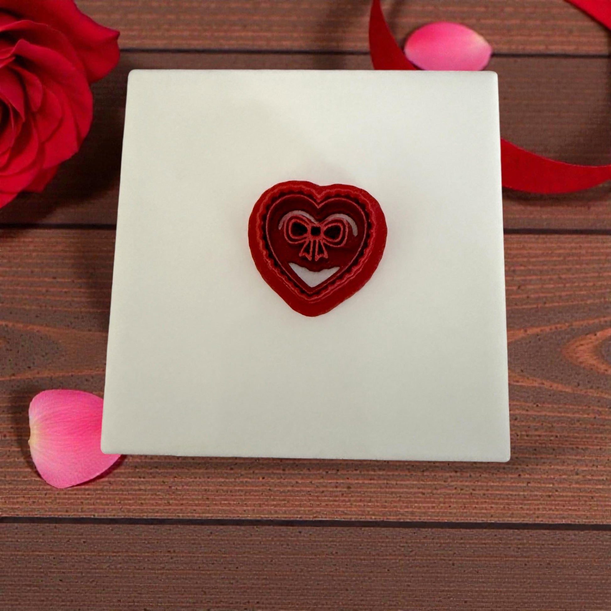 Heart bow cutter displayed on white tile with rose petals