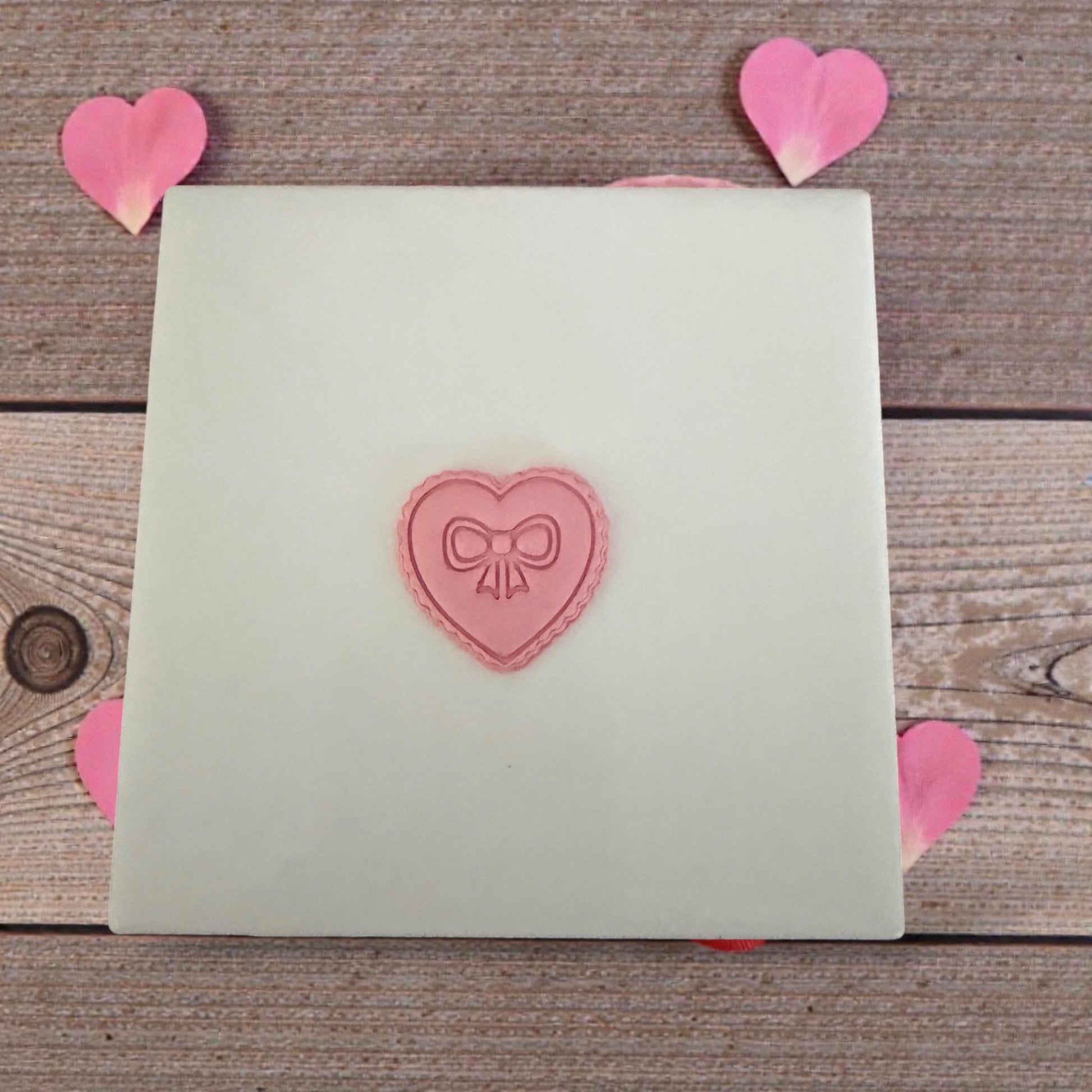 Heart bow clay impression on white tile with scattered petals