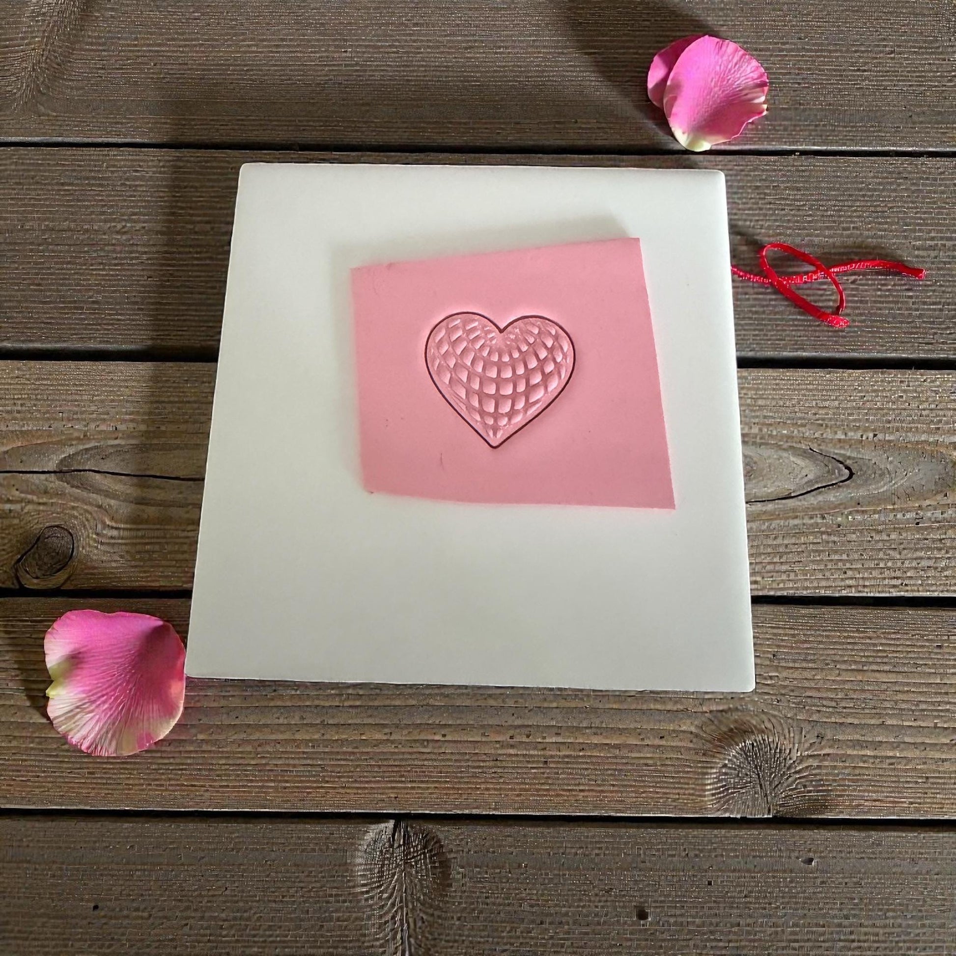 pink heart clay imprint on tile with petals around