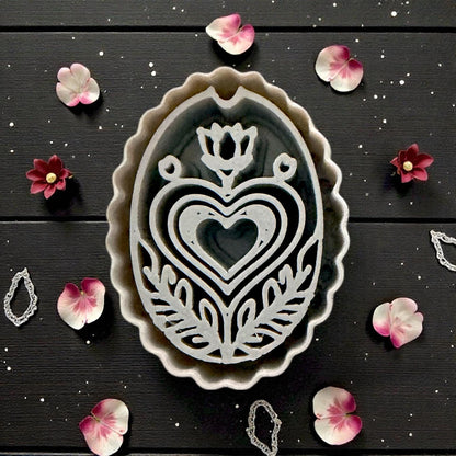 closeup of grey cutter next to pink clay folk design