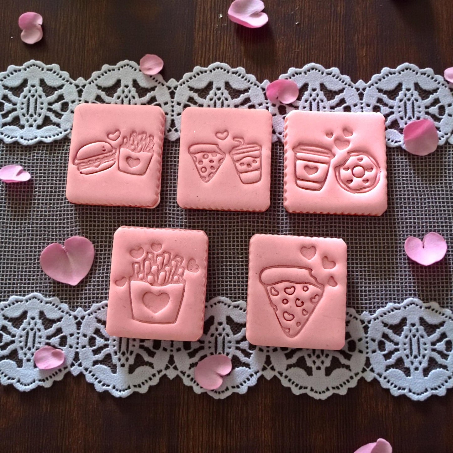 Five pink clay impressions of Valentine food cutter designs on lace mat