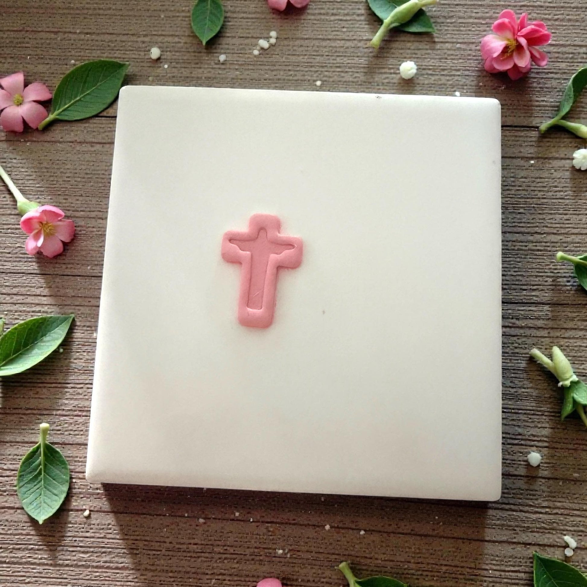 tiny pink clay cross on tile