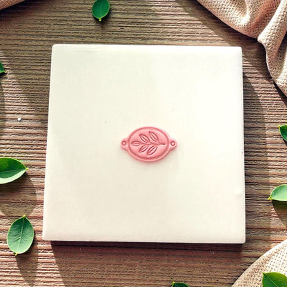 small clay leaf bracelet charm on ceramic tile