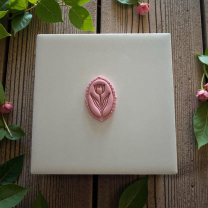 Single tulip clay cameo on white tile with greenery