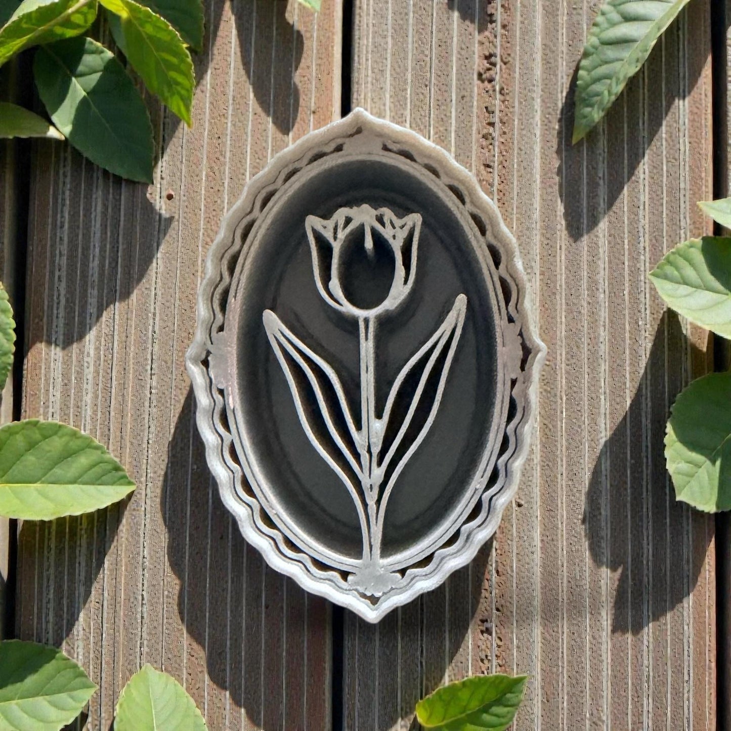 Oval tulip cameo polymer clay cutter on wood background with leaves