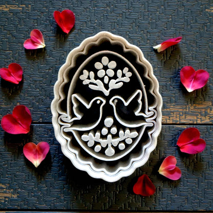 Closeup gray oval cutter with doves and floral accents