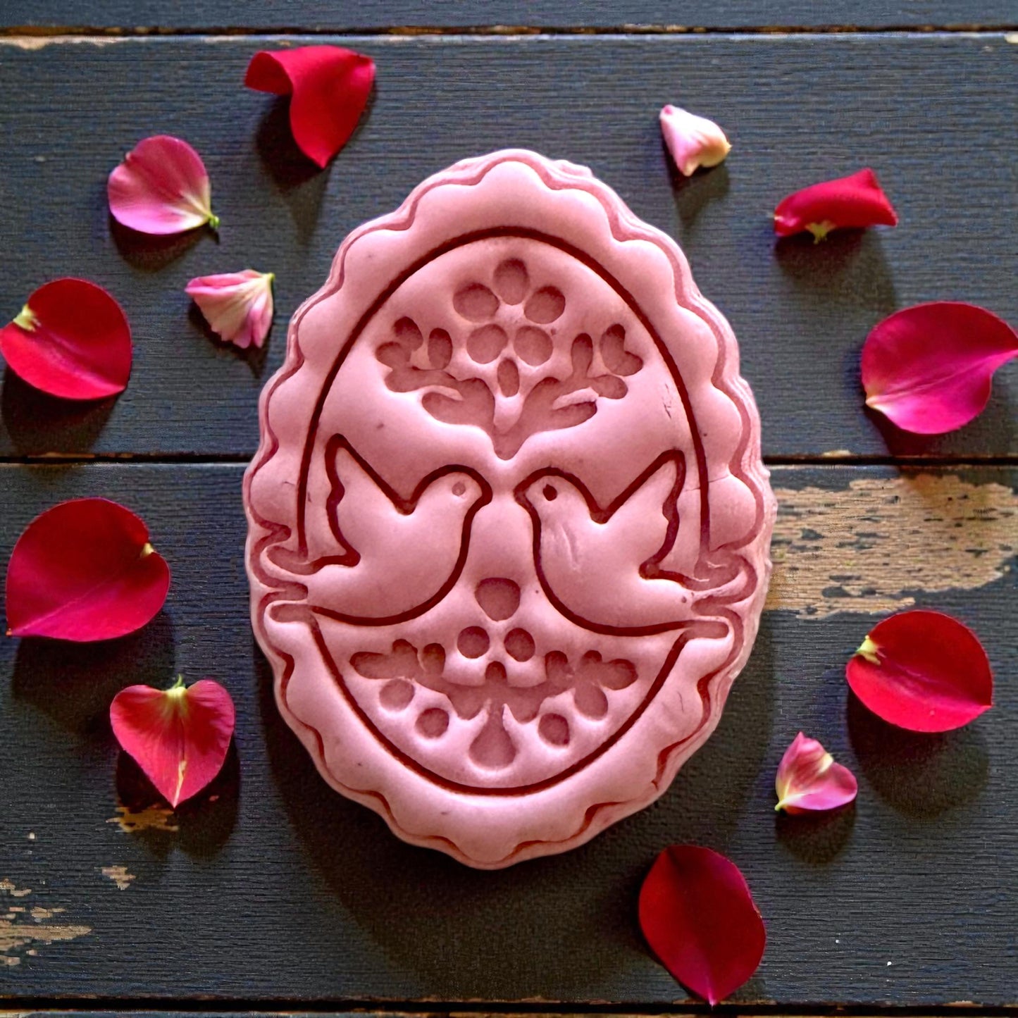 Closeup pink clay oval with doves and floral folk art details