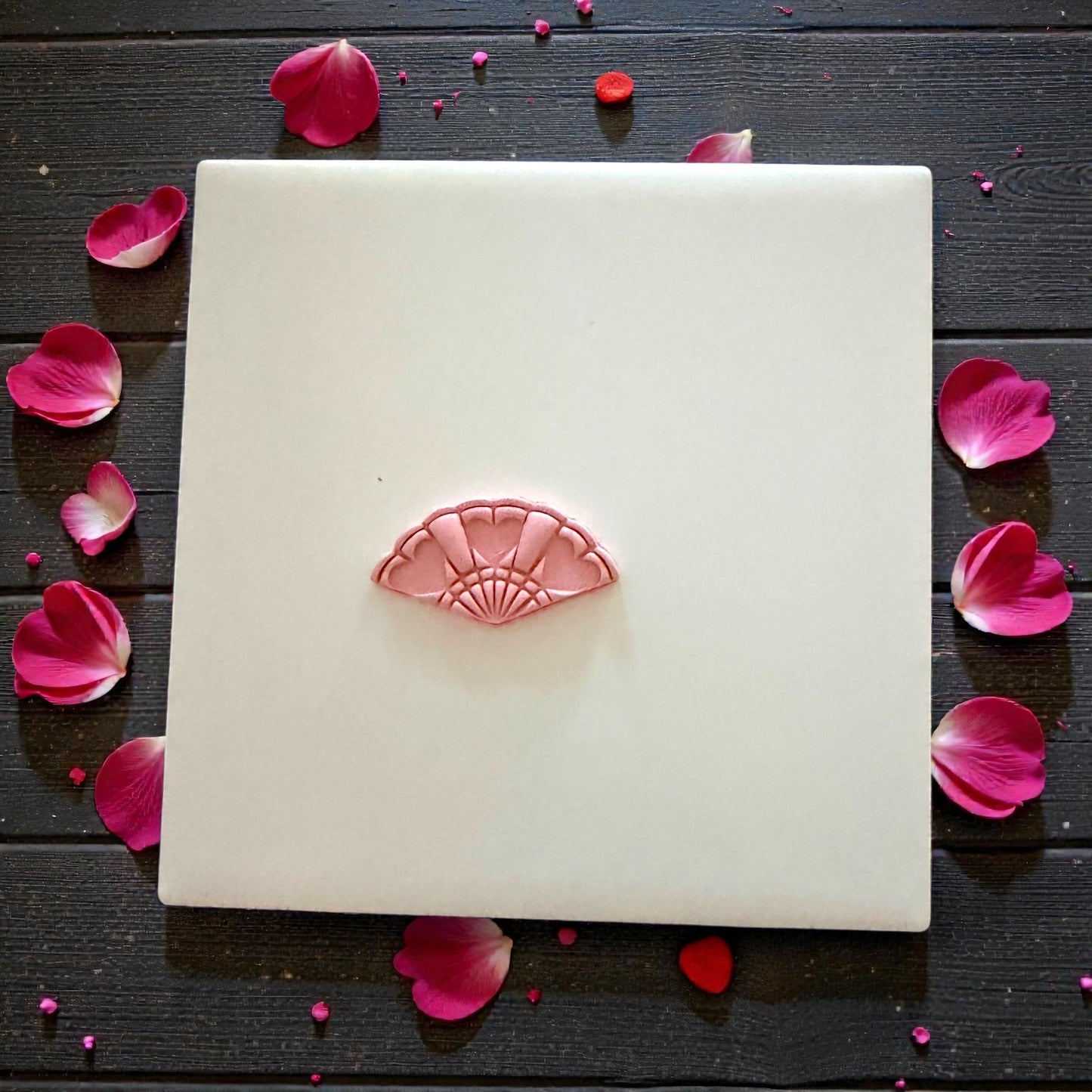 small heart fan clay impression centered on white tile with petals