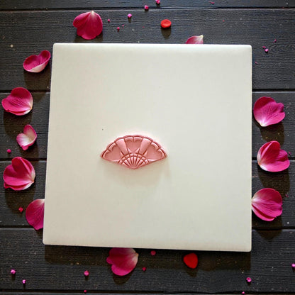 small heart fan clay impression centered on white tile with petals