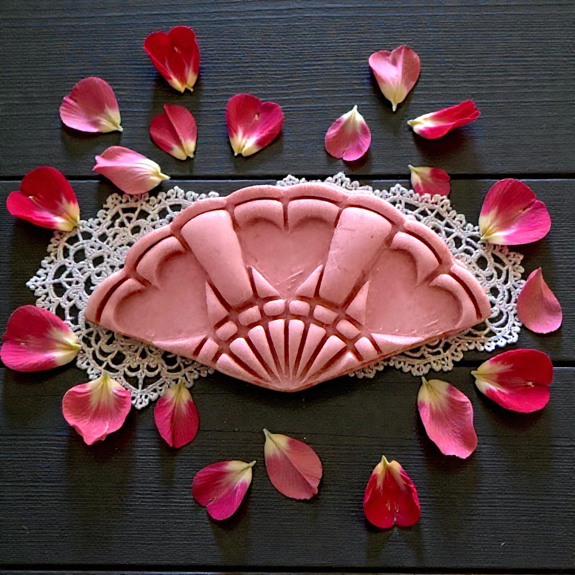 heart fan clay imprint on pink slab over white tile with scattered petals