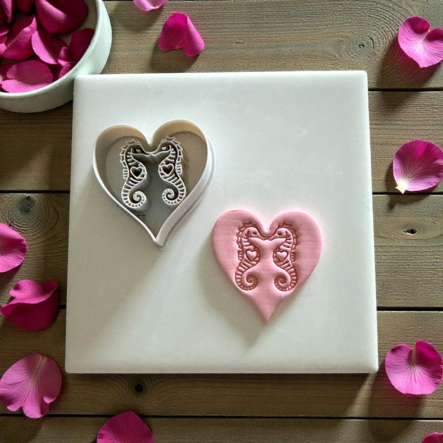 heart clay cutter and seahorse impression on white tile