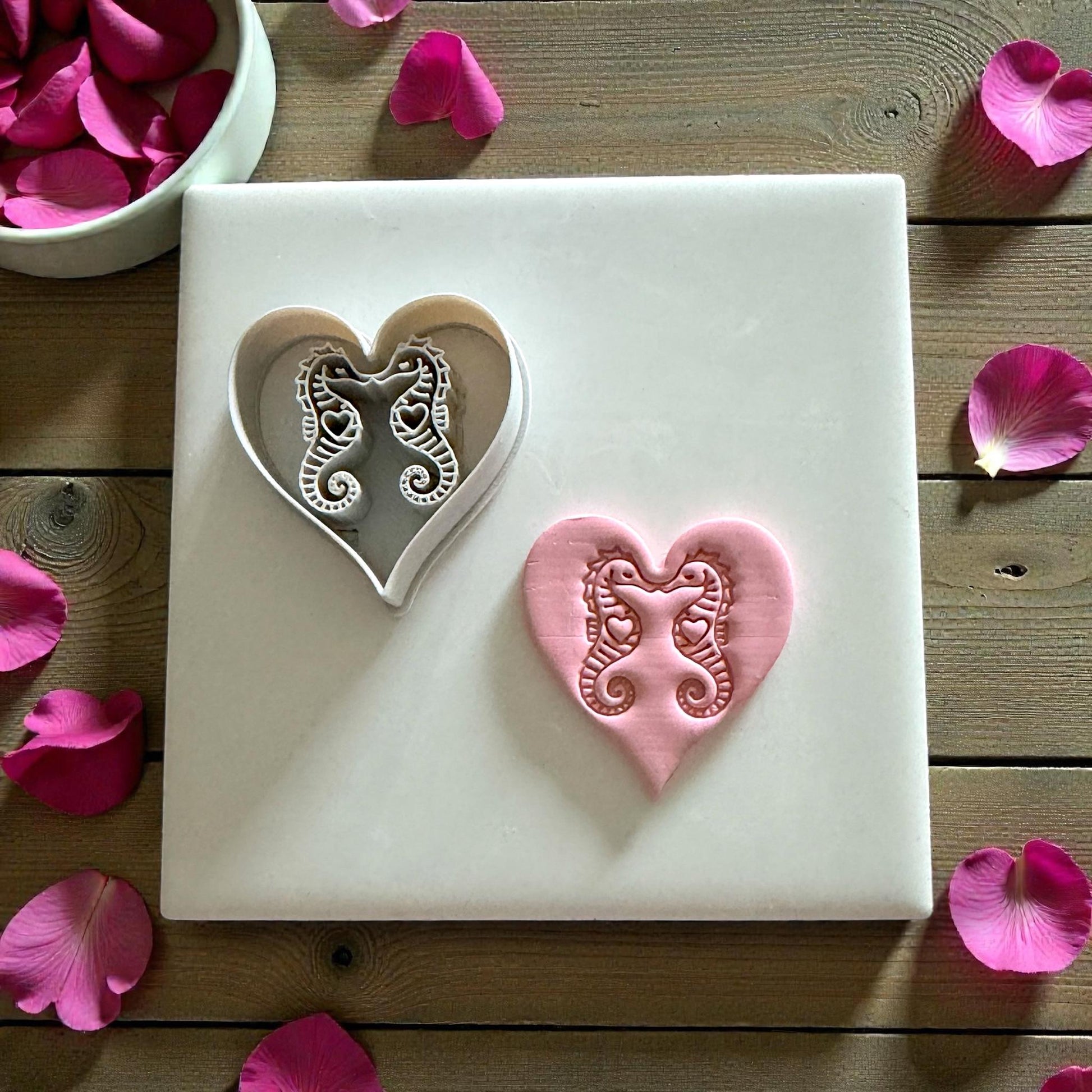 heart clay cutter and seahorse impression on white tile