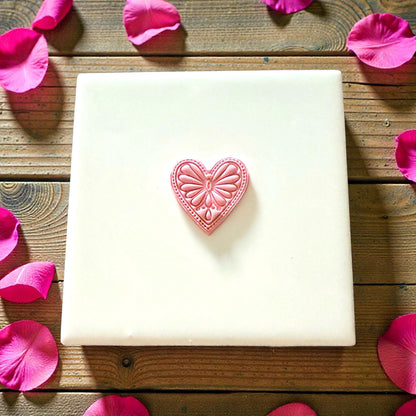 Pink boho heart impression centered on white tile with rose petals