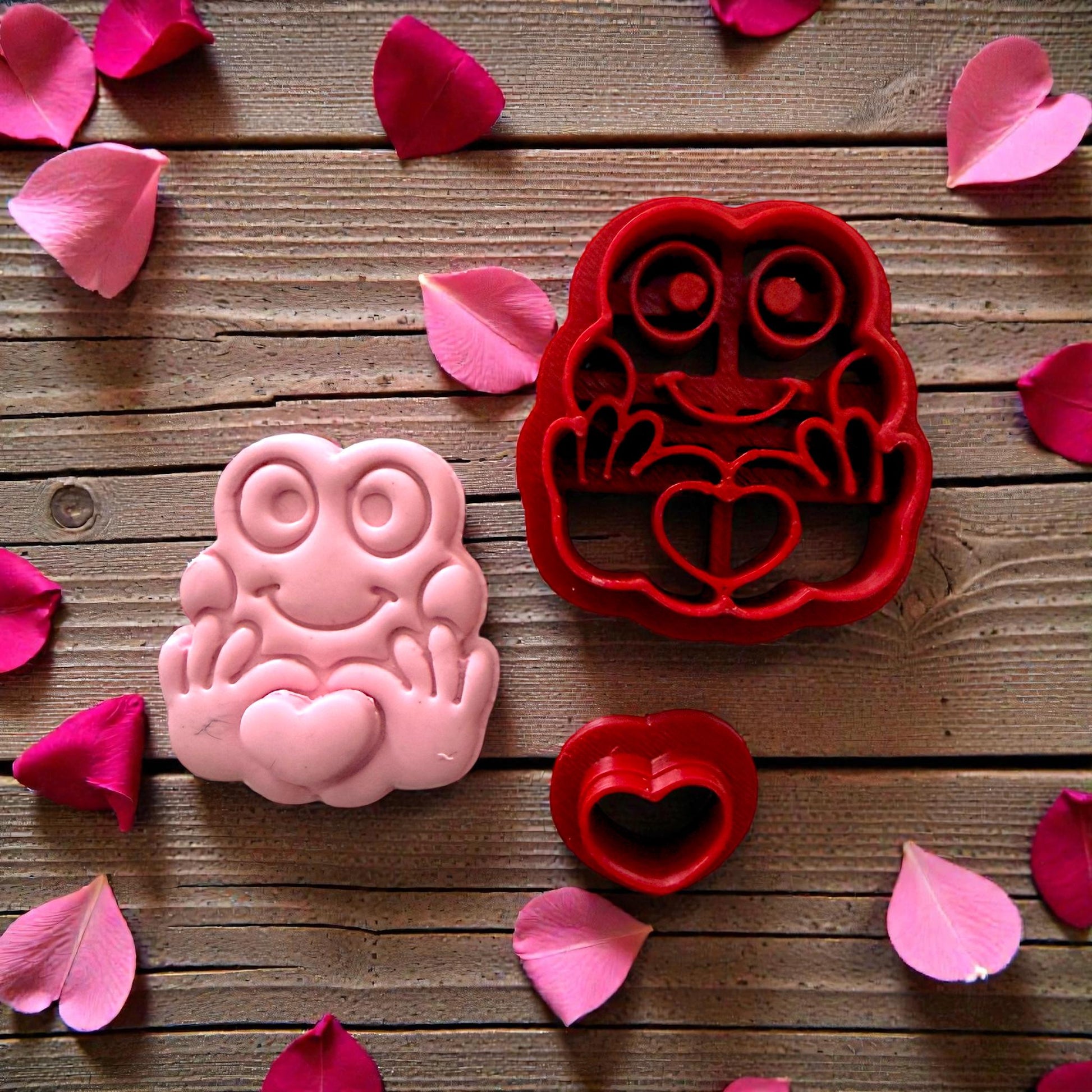 Red frog cutter and small heart cutter displayed on white tile