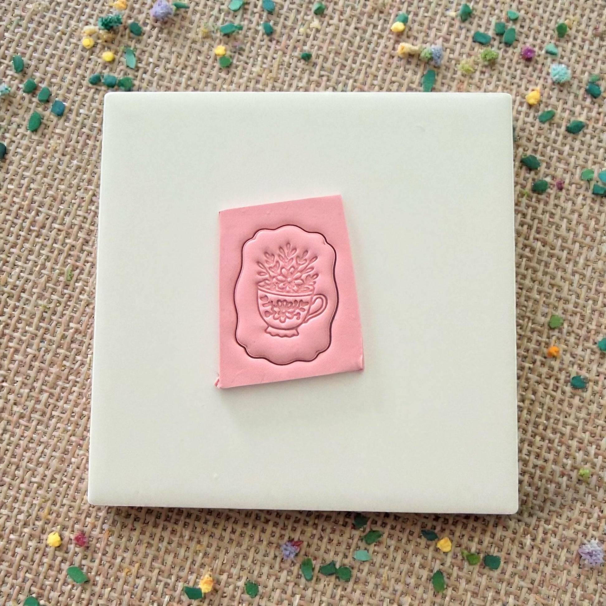 floral teacup clay stamp pressed into pink clay on tile