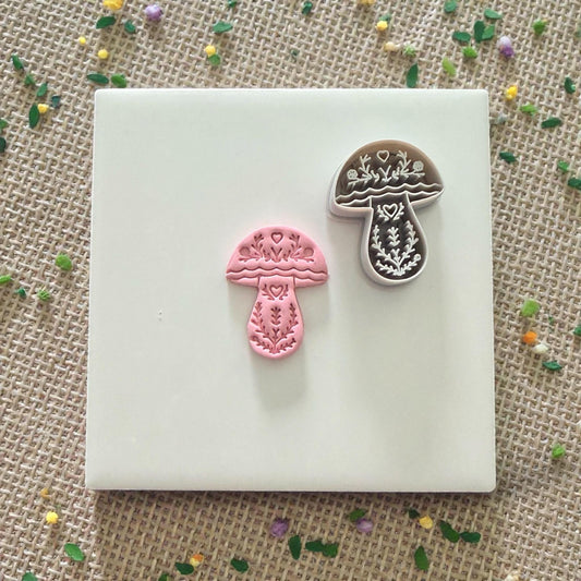 mushroom clay cutter with pink clay impression on tile