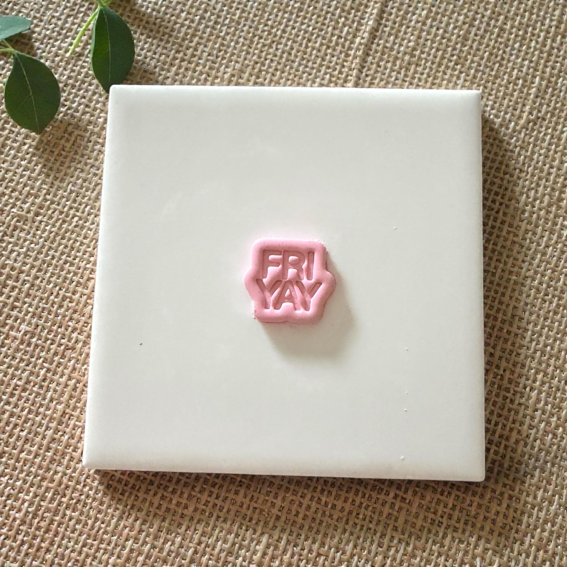 Pink FRIYAY clay piece centered on white tile