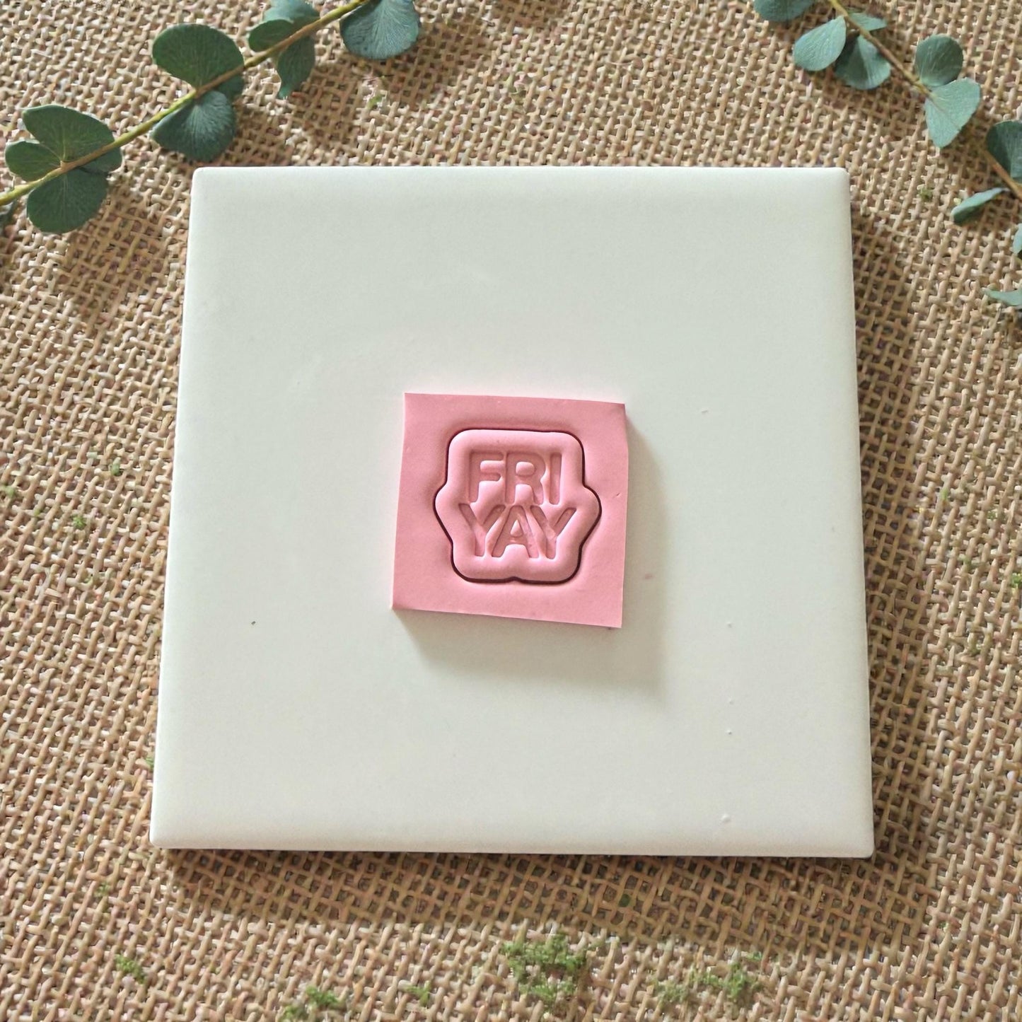 FRIYAY stamp impression on pink clay rectangle with greenery