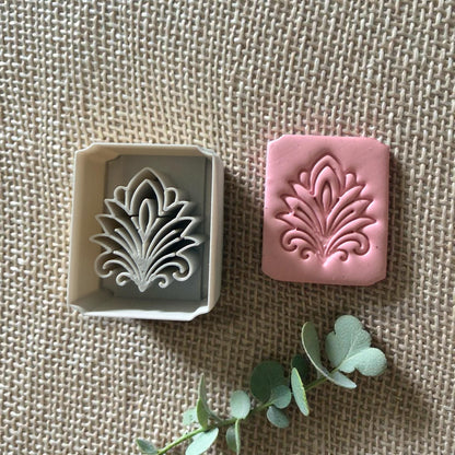 floral tile cutter next to pink clay impression
