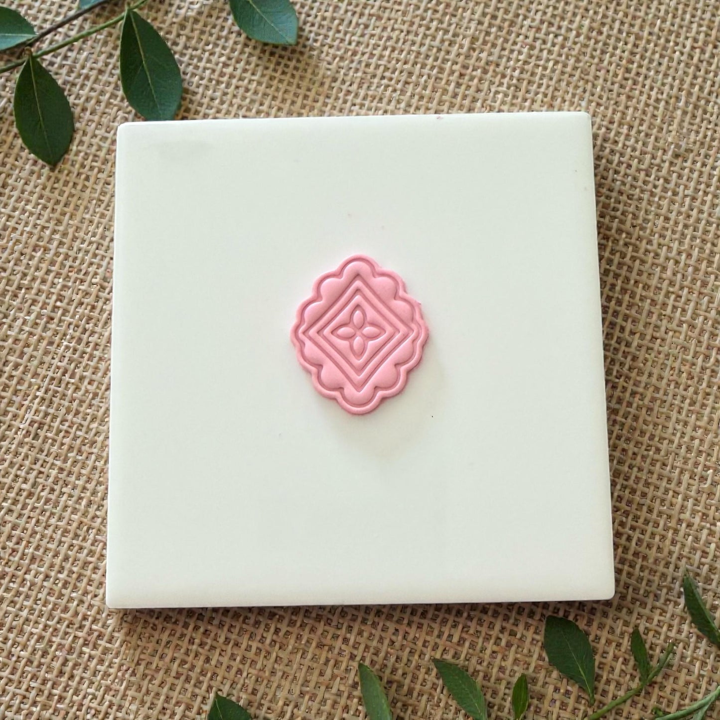 small pink scalloped tile impression on white tile