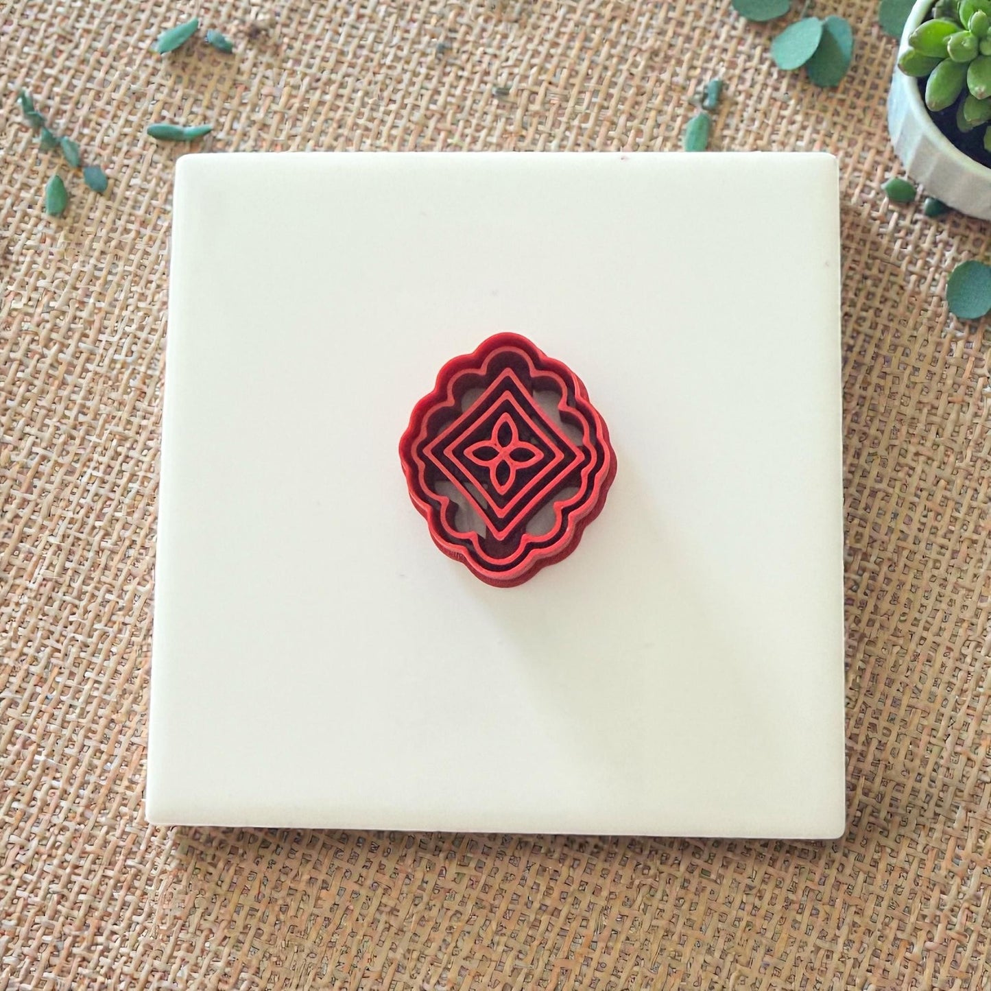 red scalloped tile cutter centered on white tile