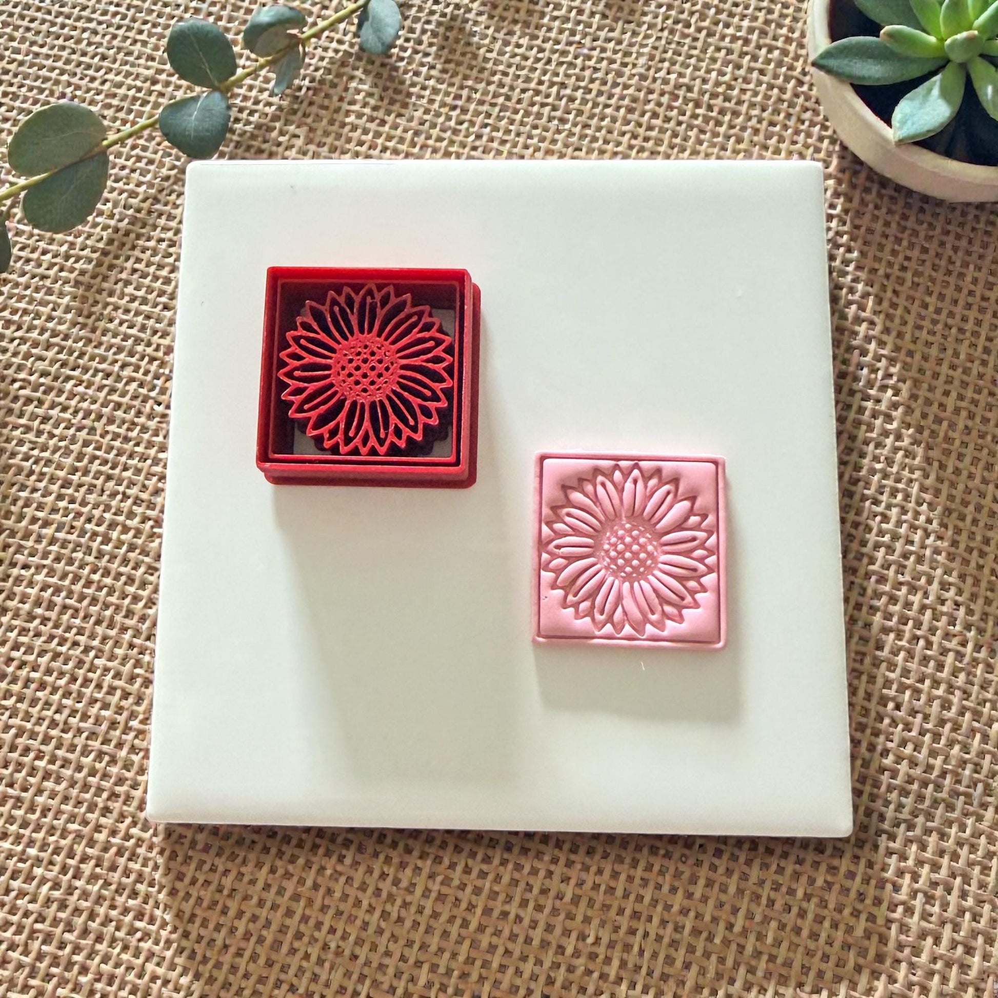 red sunflower cutter with pink clay impression side by side on white tile