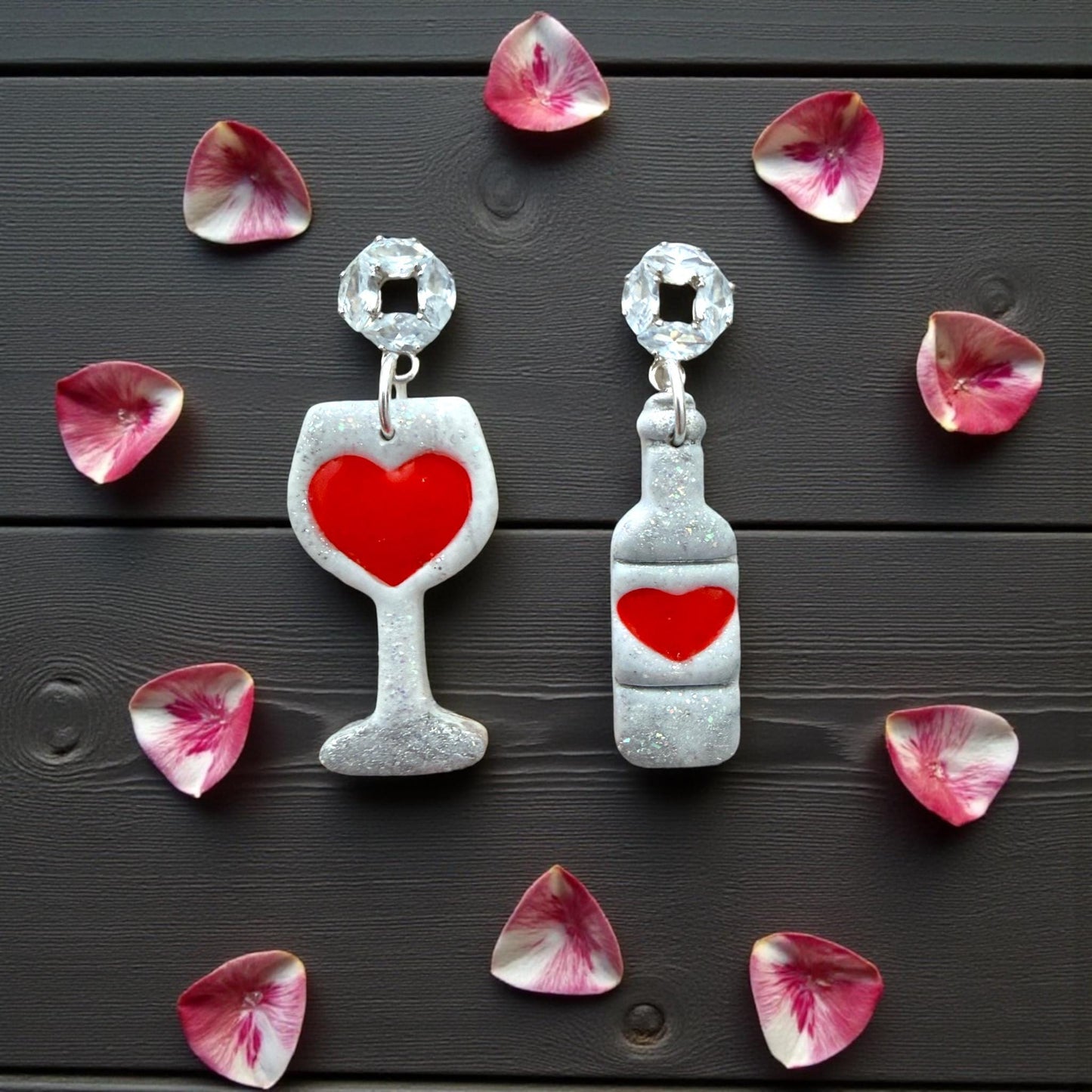 Wine glass and bottle earrings surrounded by pink heart petals