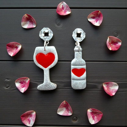Wine glass and bottle earrings surrounded by pink heart petals