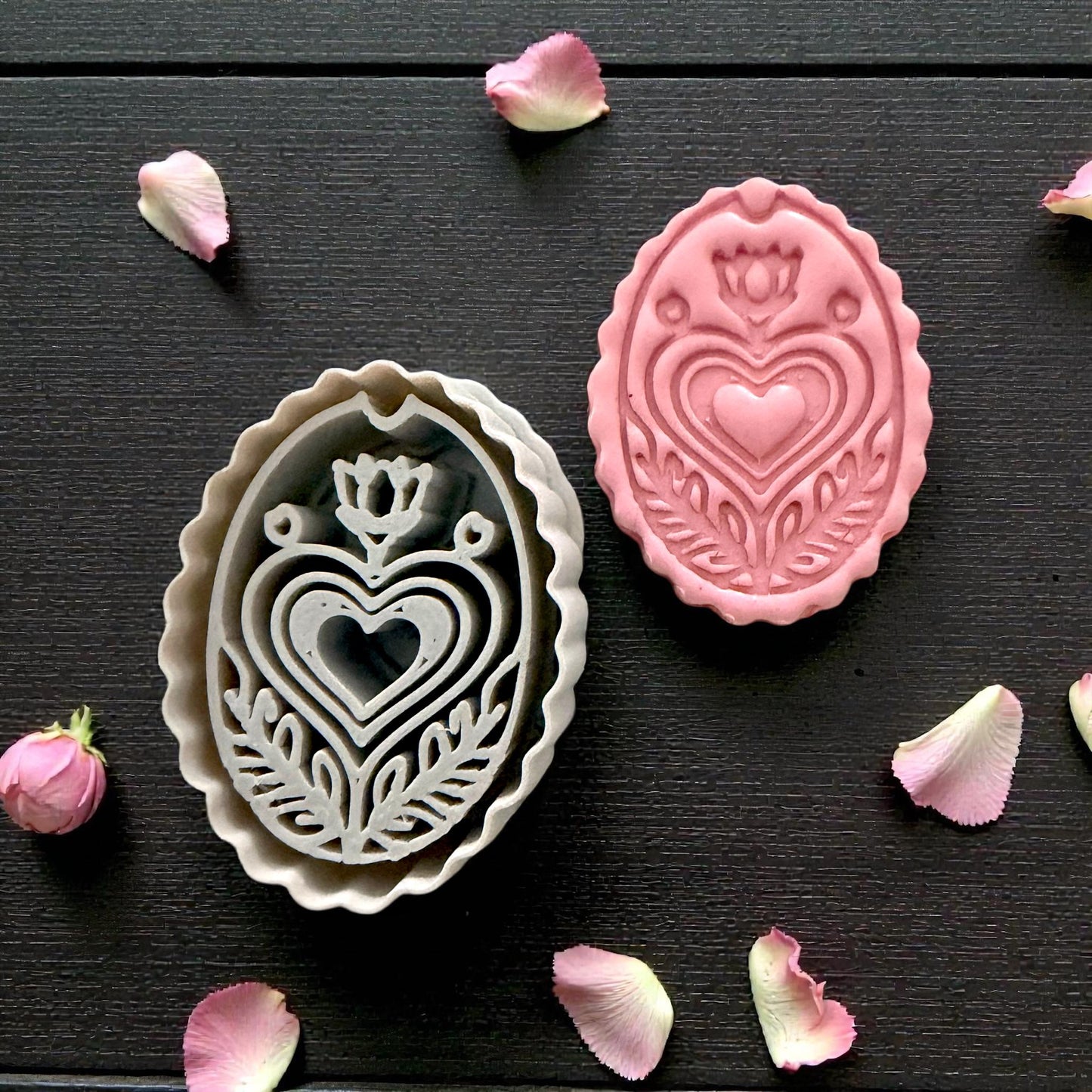 grey cutter and pink folk heart clay piece side by side