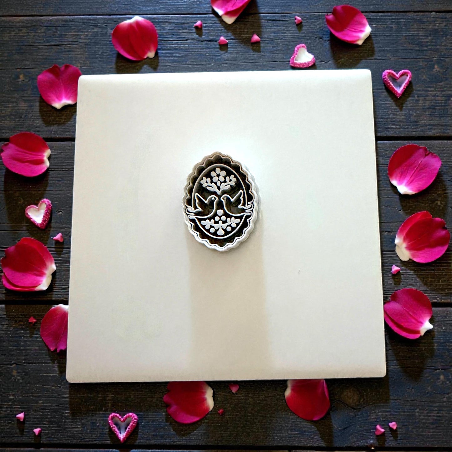 Gray cutter on tile surrounded by pink rose petals and hearts