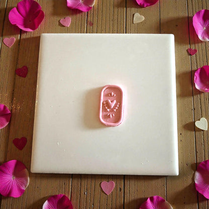 small heart plaque clay piece centered on white tile