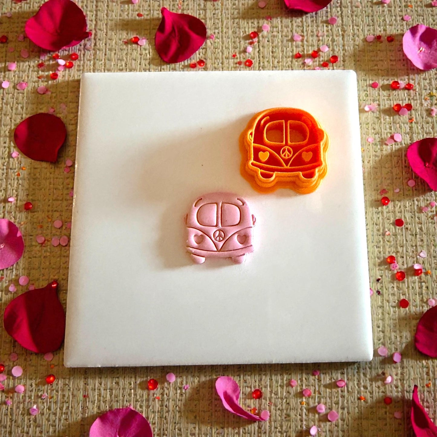orange love bus cutter and pink clay piece on white tile