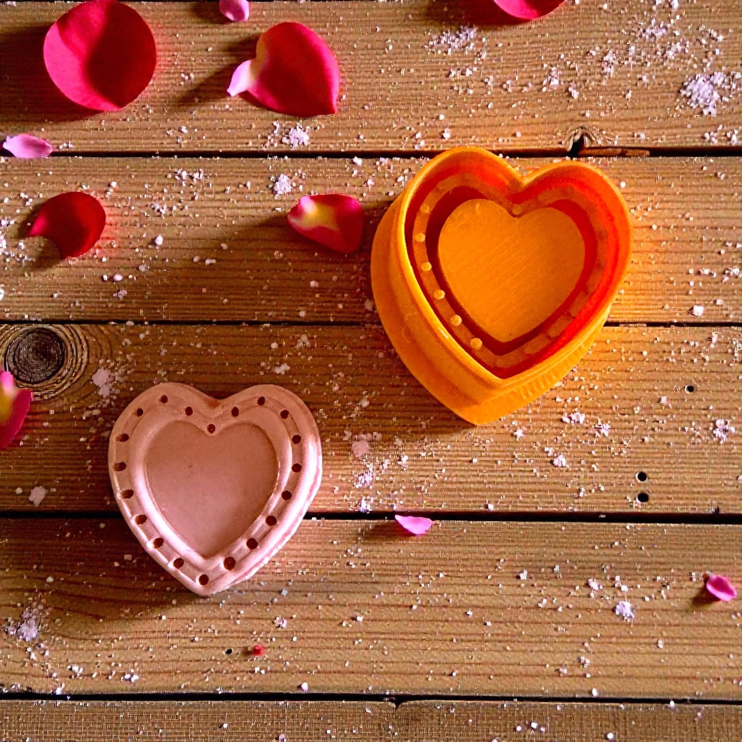 pink dotted heart and orange cutter shown on wood background