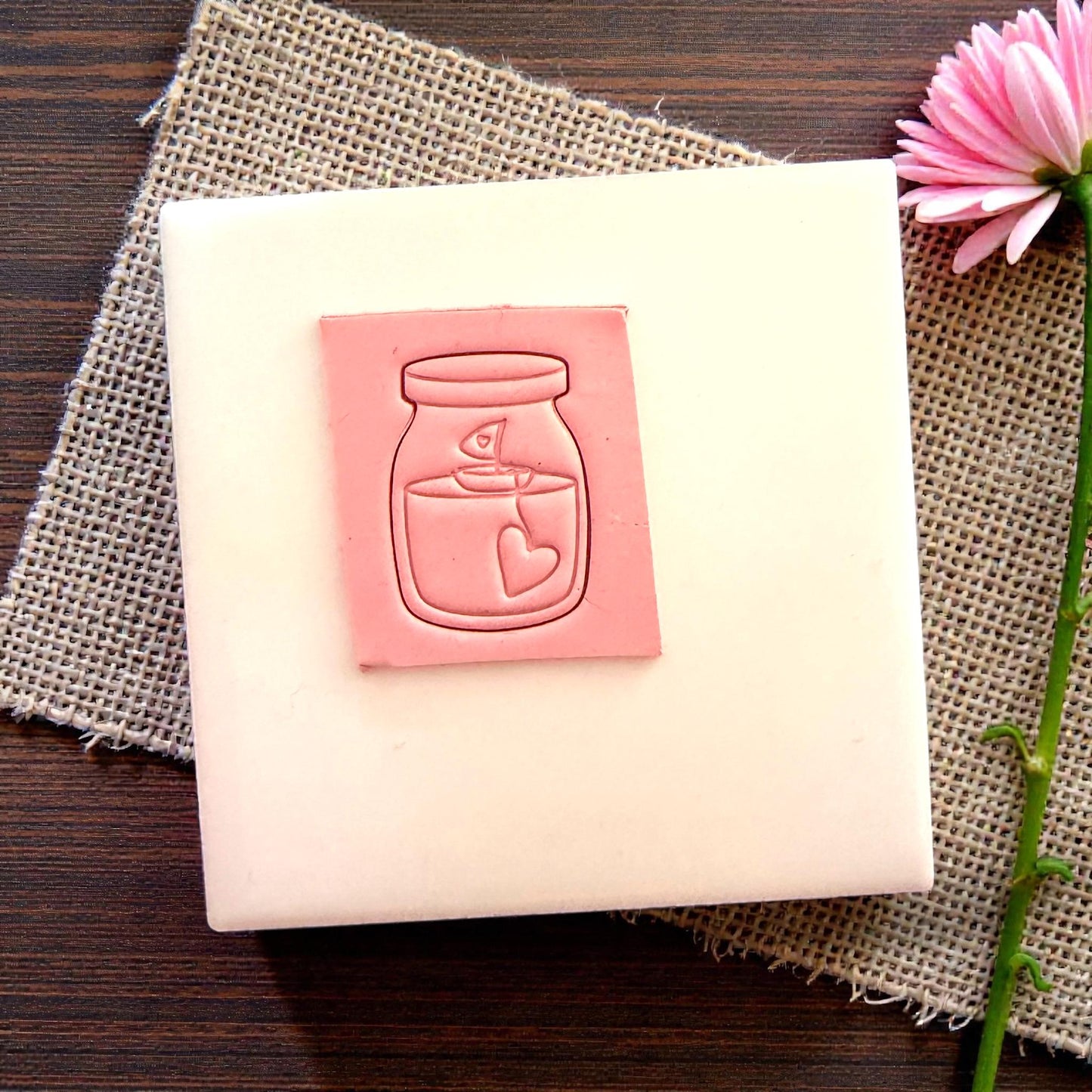 Pink clay impression of candle jar cutter on tile